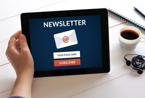 Hand holding digital tablet computer with subscribe newsletter c